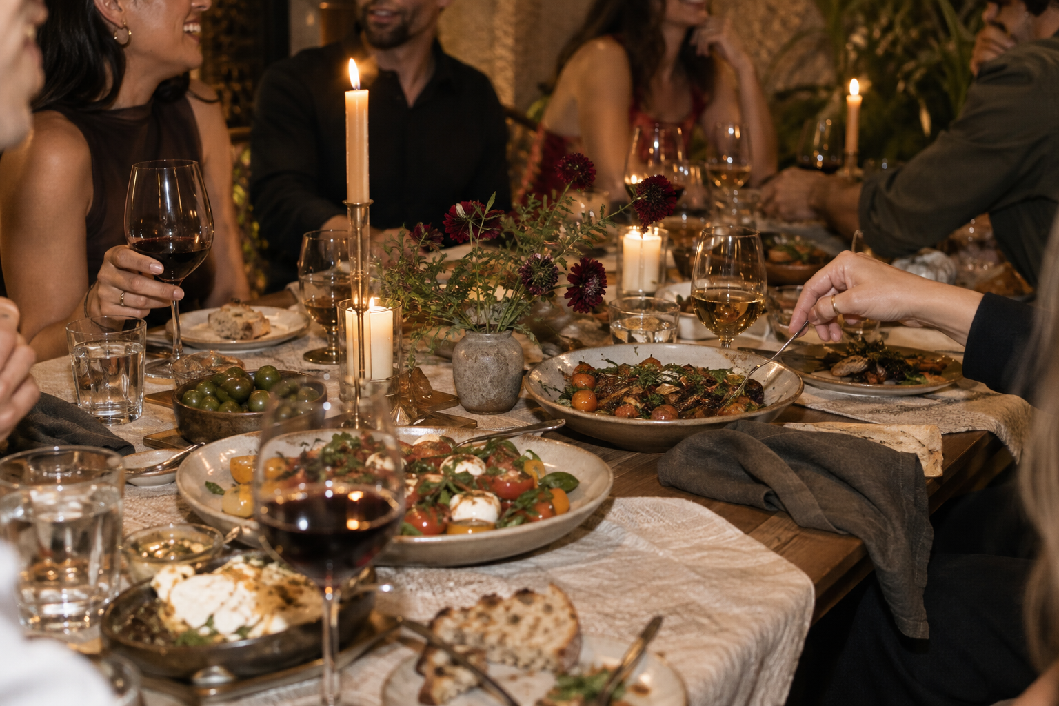 Lively dinner table with candles, shared food, and guests